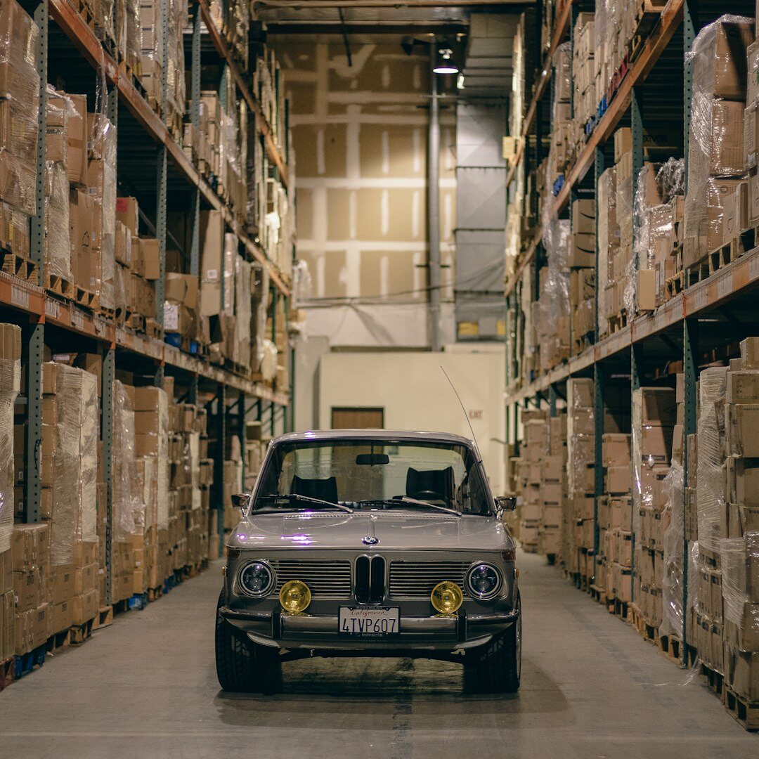 Warehouse filled with rare classic automobiles under warm industrial lighting