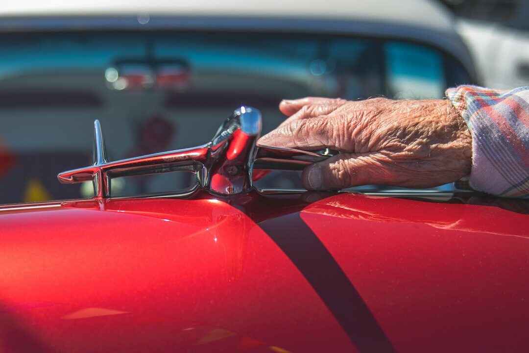 Hands examining historical automobile documents and photographs with a magnifying glass